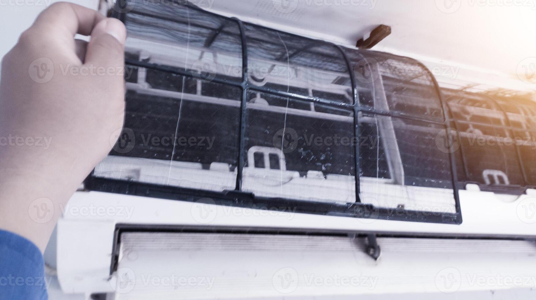 The concept of carrying out maintenance on the room air conditioning, a service technician cleaning the filter on the indoor air conditioning section,Maintenance process on the room air conditioning. photo