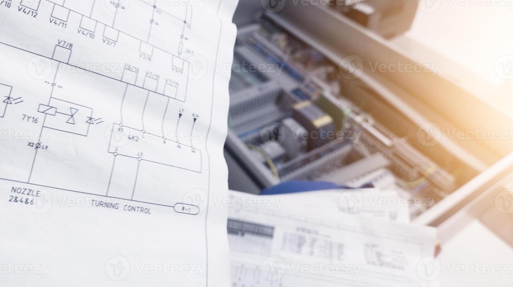 Looks at the electrical drawing on the background of the automation panel.For conceptual analysis trouble shooting electrical control. photo