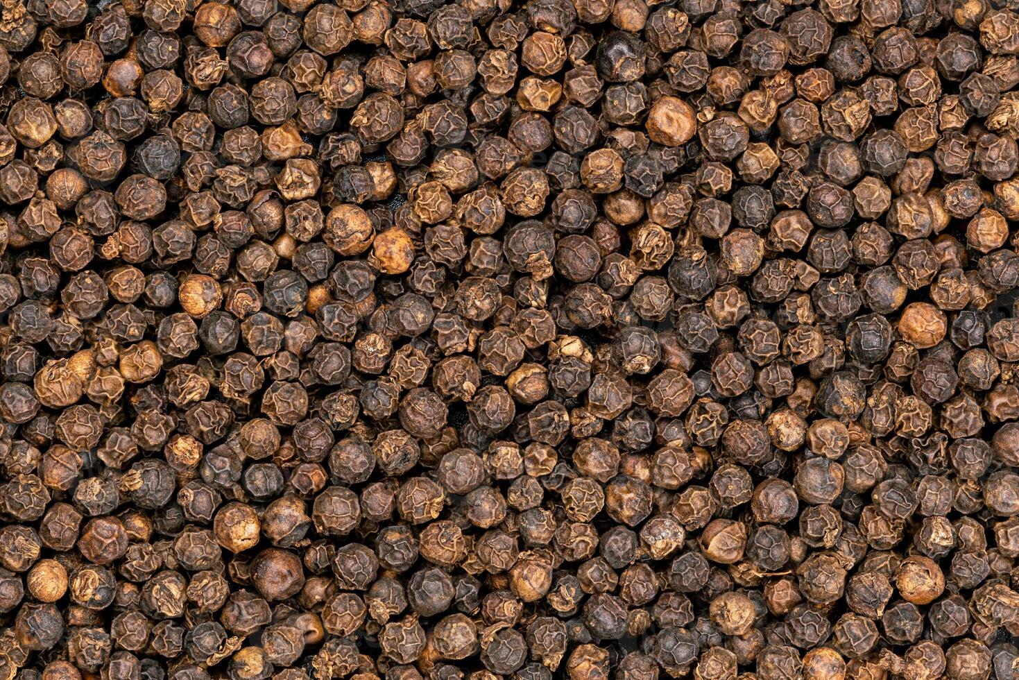 Top view pile of black pepper, full frame, use as a background. Closeup view of dried black peppercorn. photo