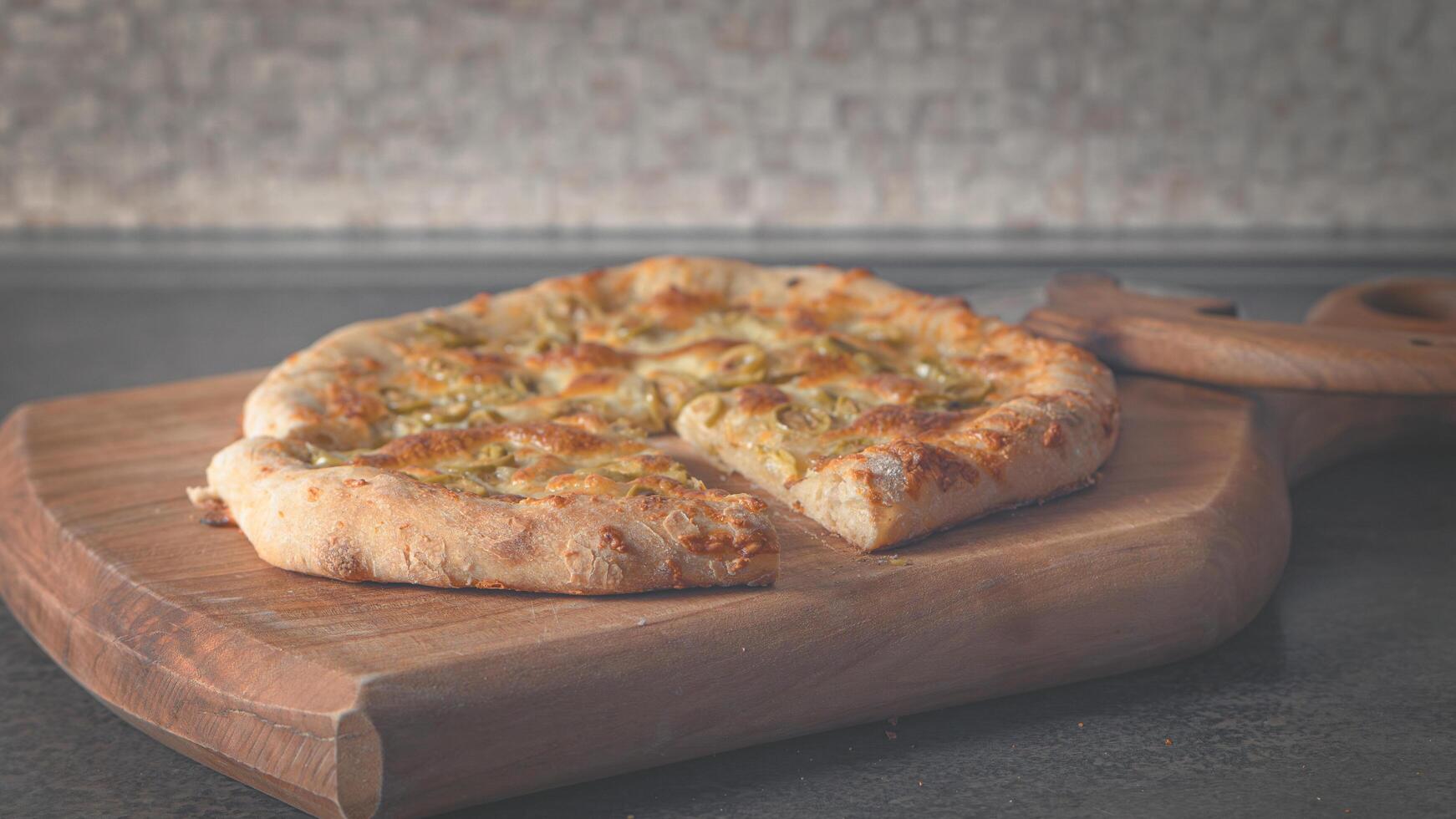 Pizza con suluguni Olivos. Pizza cuchillo en un de madera tablero. 16-9 foto