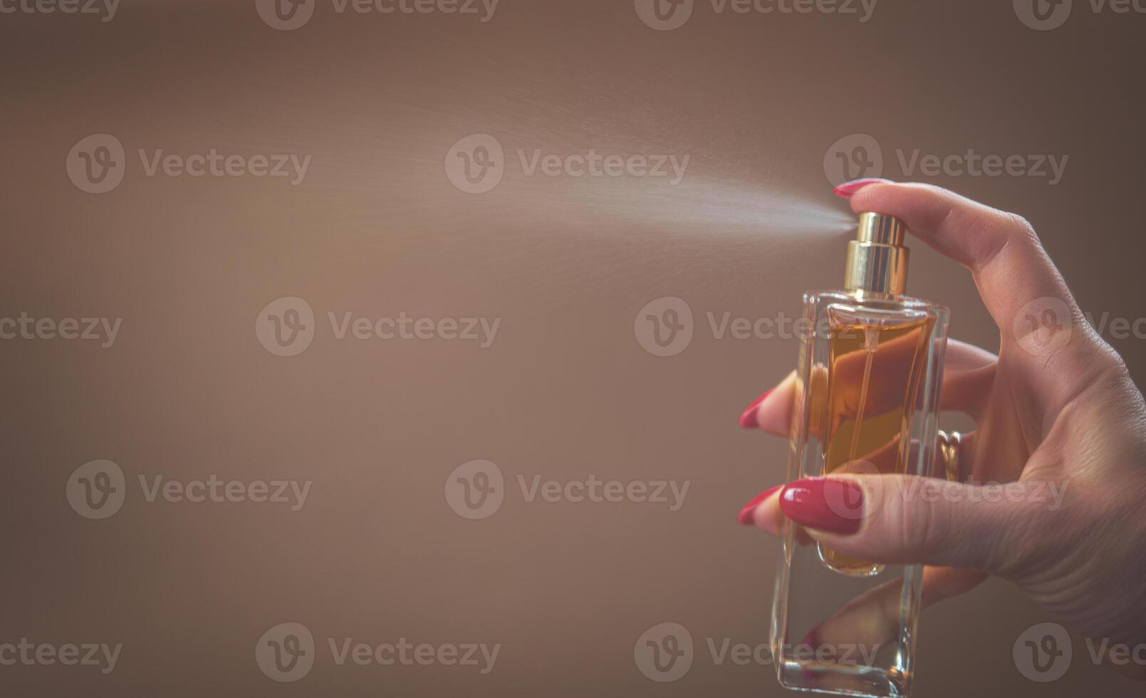 A woman holds a bottle of perfume in her hand without a cap. Close-up photo