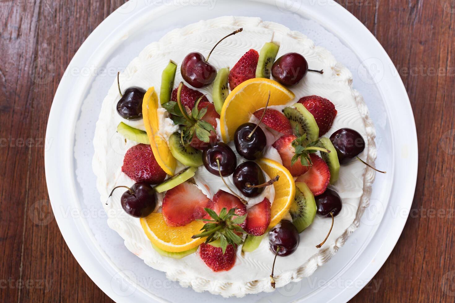 Top view of delicious cake with different kinds of fruits topping photo