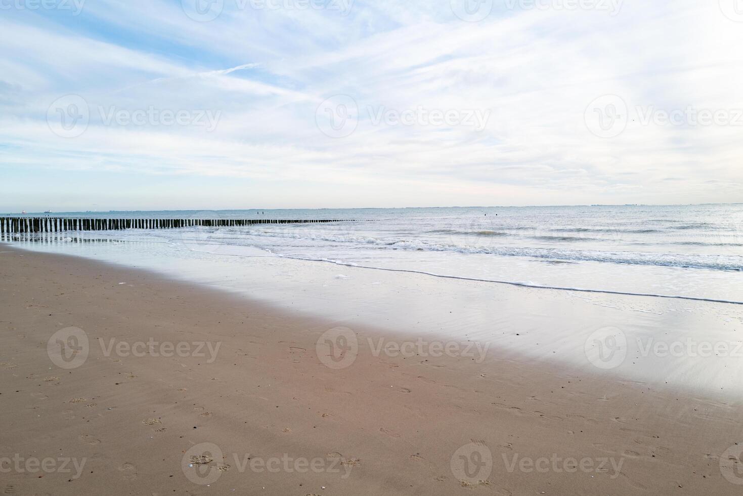 lonely beach with waves and sky in zeeland, the netherlands photo