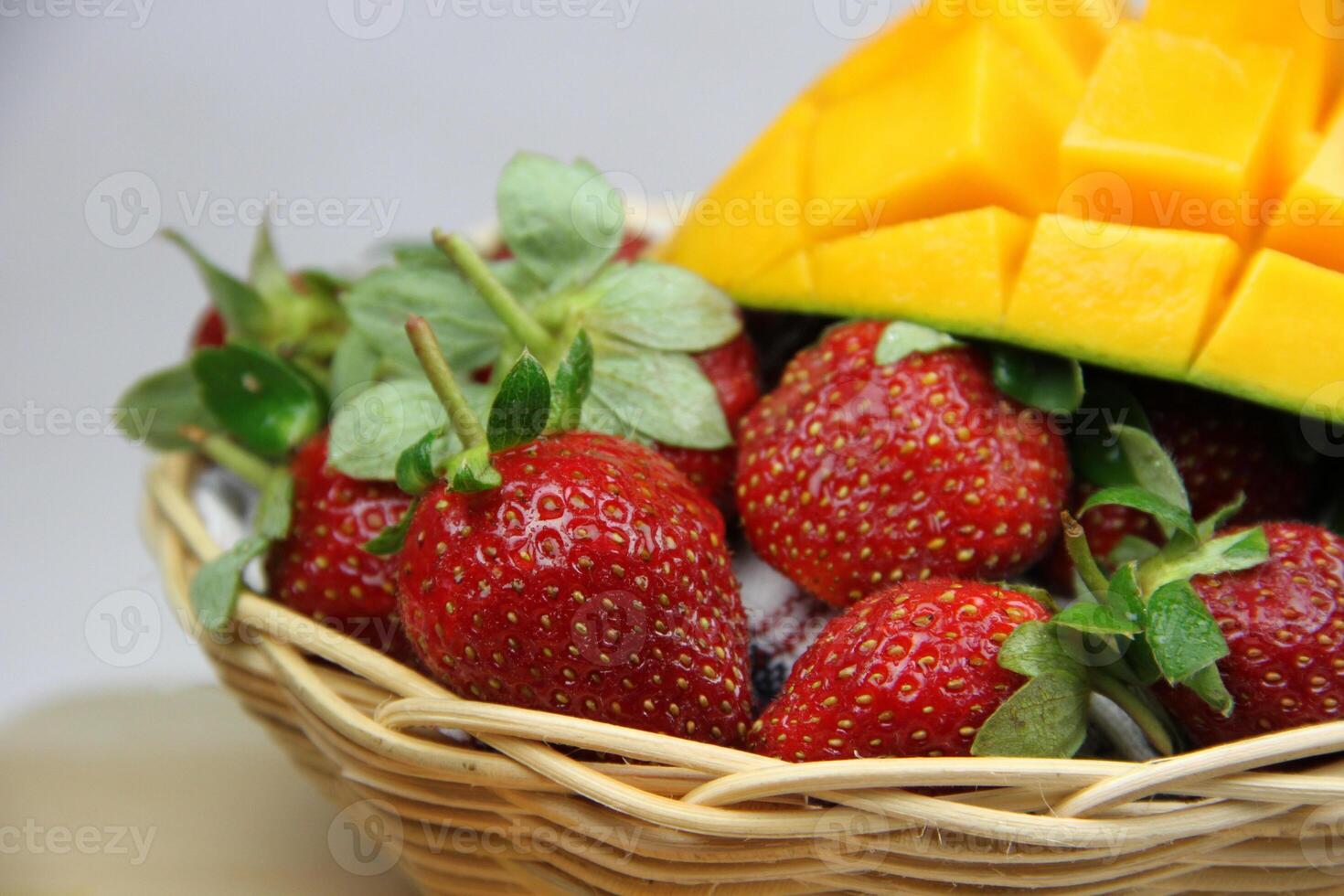 un cesta de fresas y mangos en el corte tablero en blanco antecedentes foto