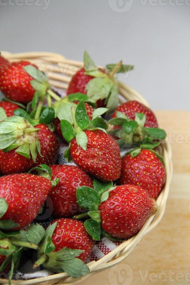 un cesta de fresas en un de madera cortar tablero en blanco antecedentes foto