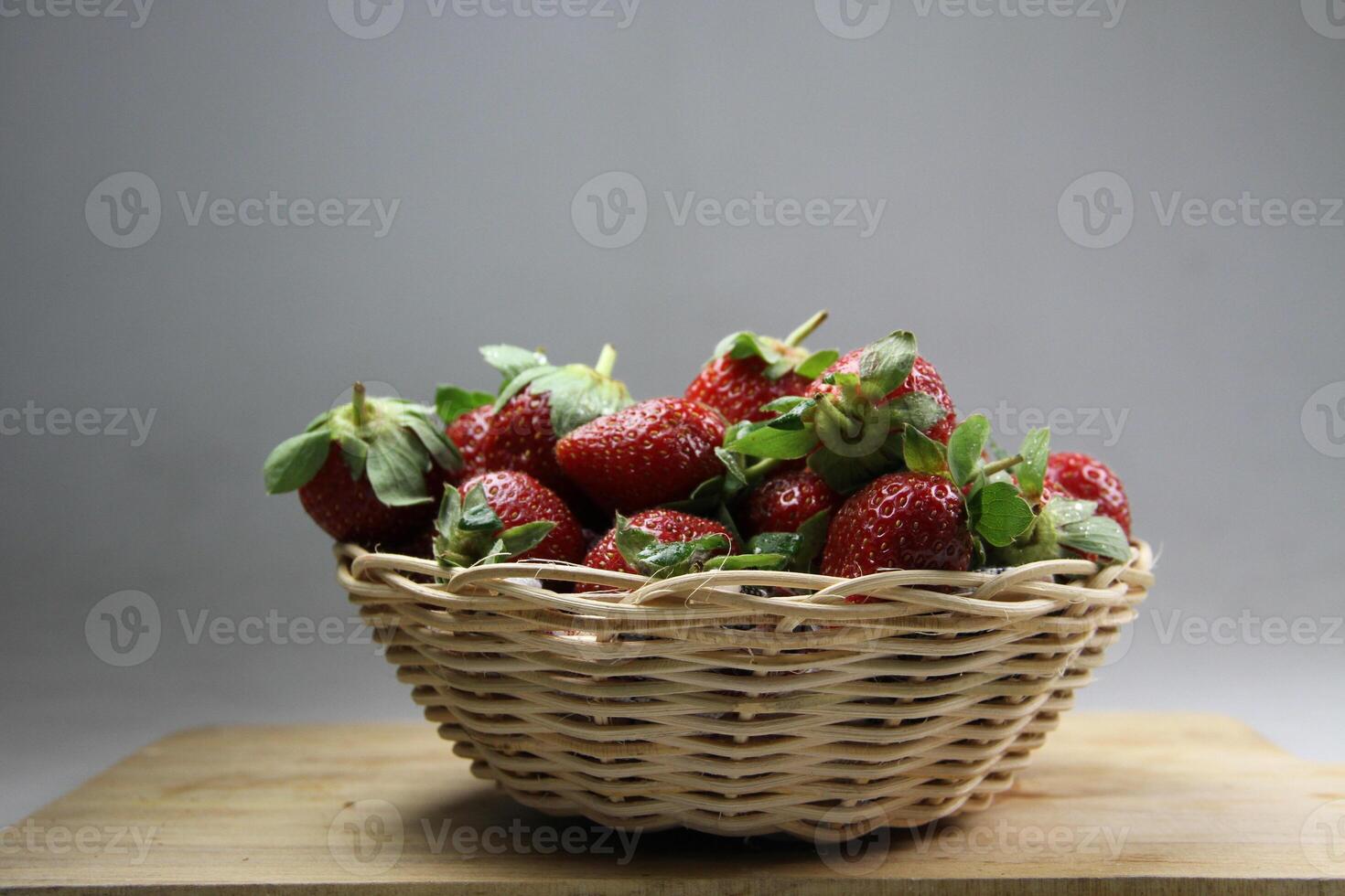 un cesta de fresas en un de madera cortar tablero en blanco antecedentes foto
