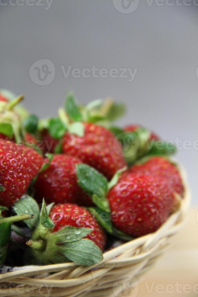 un cesta de fresas en un de madera cortar tablero en blanco antecedentes foto