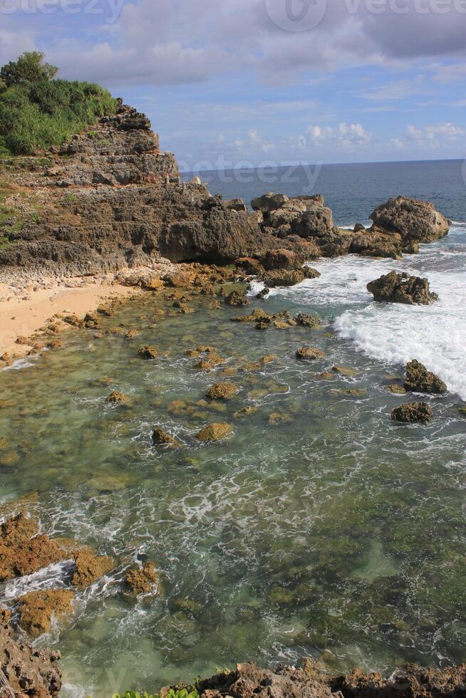 rocky beach. beach with many rocks and corals. blue sky background and rough wave photo