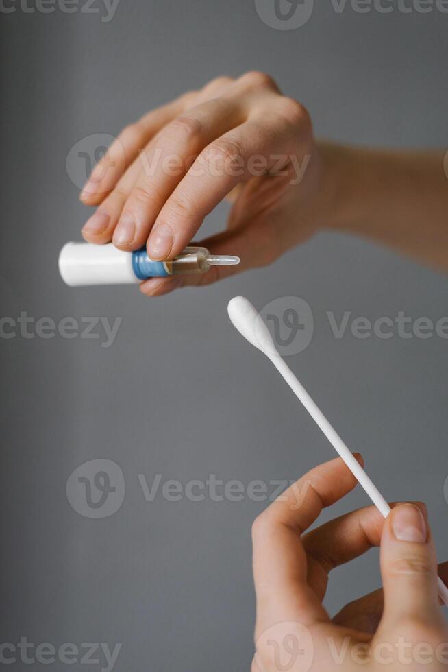 Doctor drips medicine from a jar onto a cotton swab. Close up of hands photo