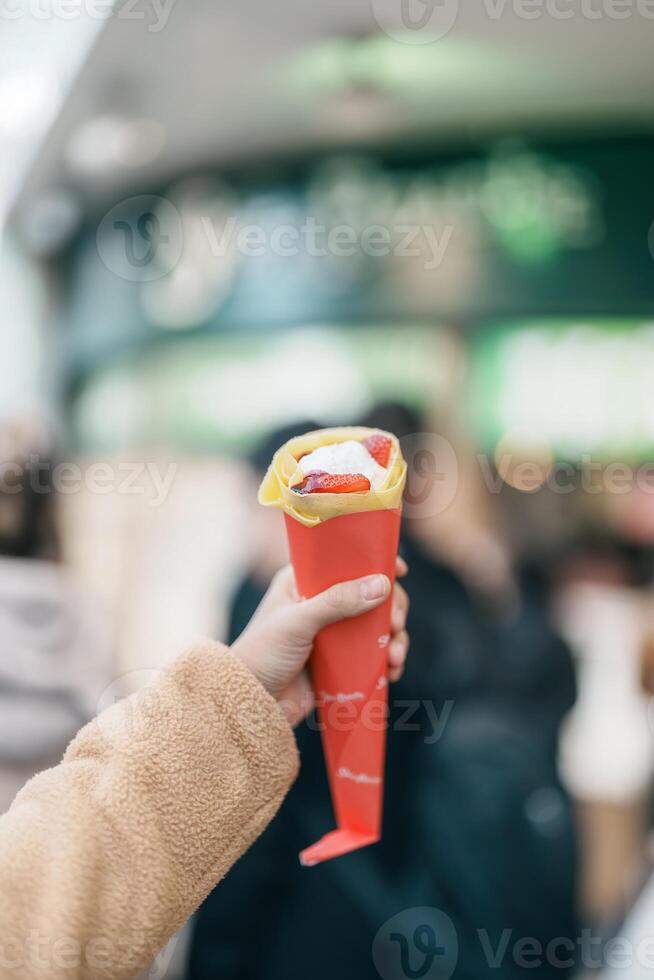 Woman hand holding Strawberry Crepes. Popular dessert pancakes in Japan photo