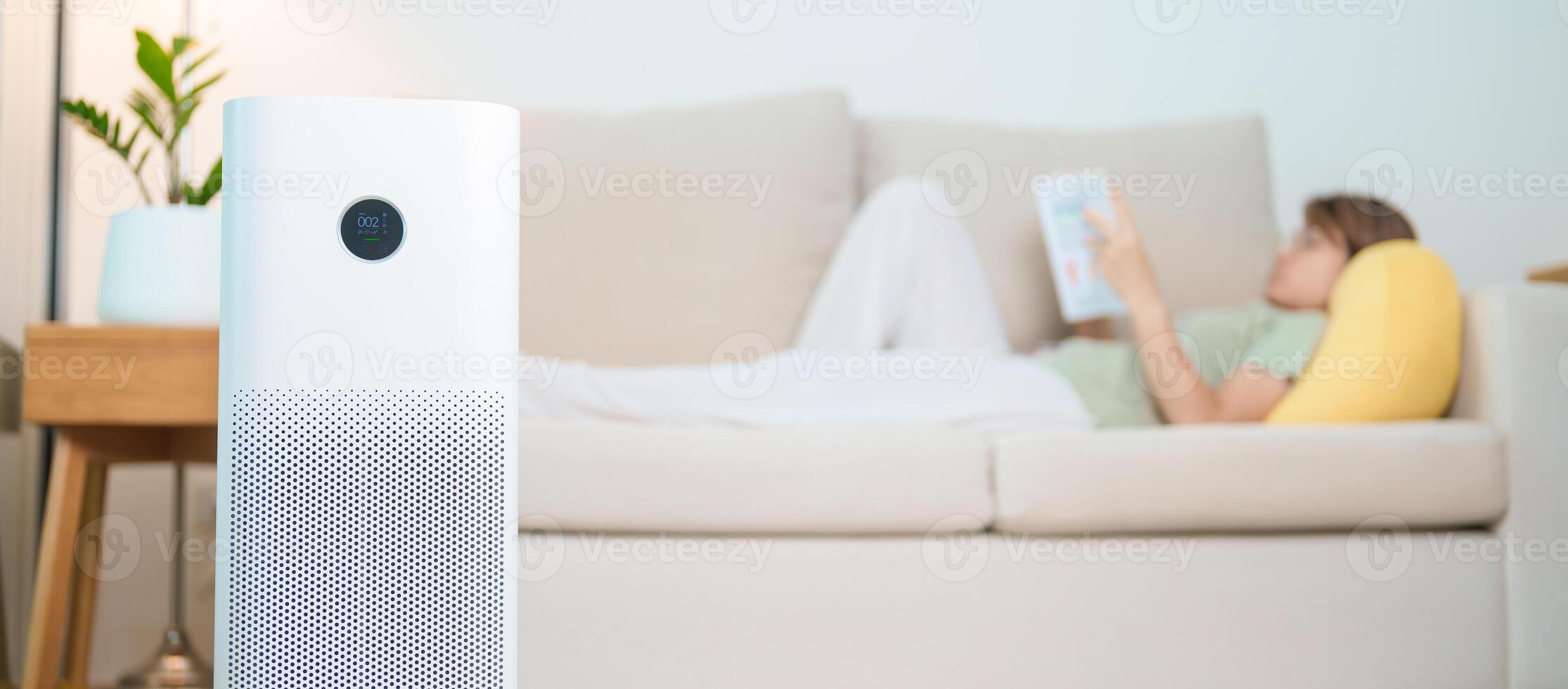 Air Purifier with woman read and relax on sofa. Purification system for filter and cleaning dust PM2.5 HEPA and virus in home. Allergy, Pure air, health lifestyle, Wellness life and Air Pollution photo