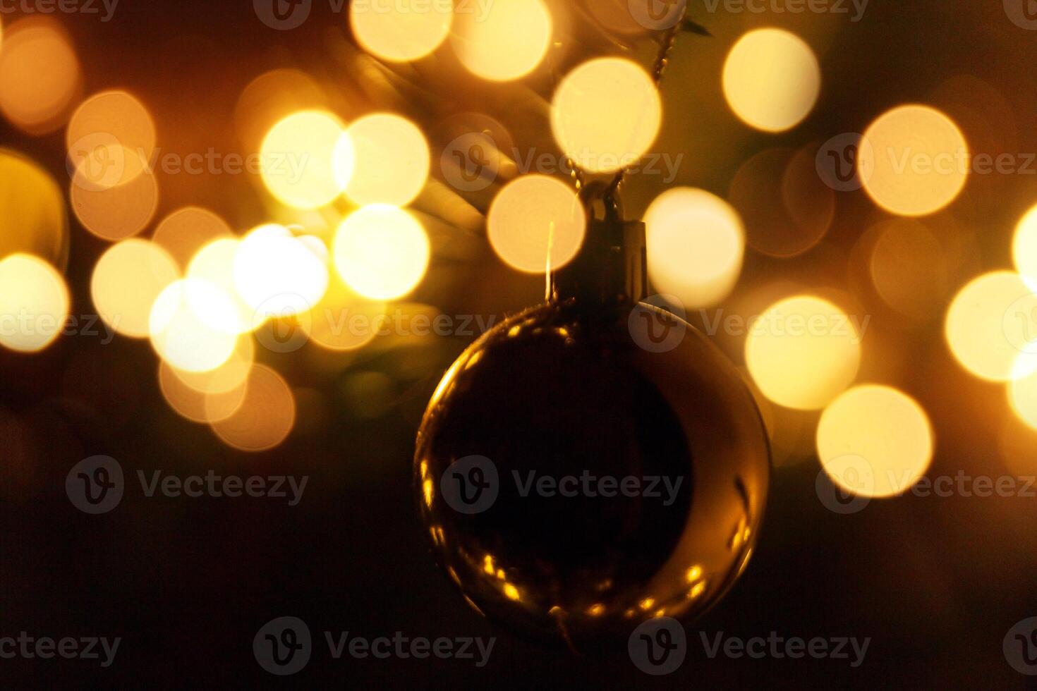 Golden ball on a Christmas tree with bokeh lights at night. Vintage Christmas card photo