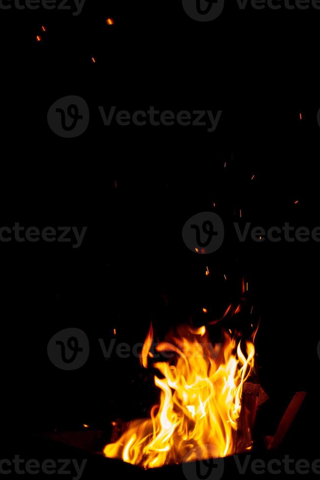 The fire burns at night. Fire and sparks on a black background photo