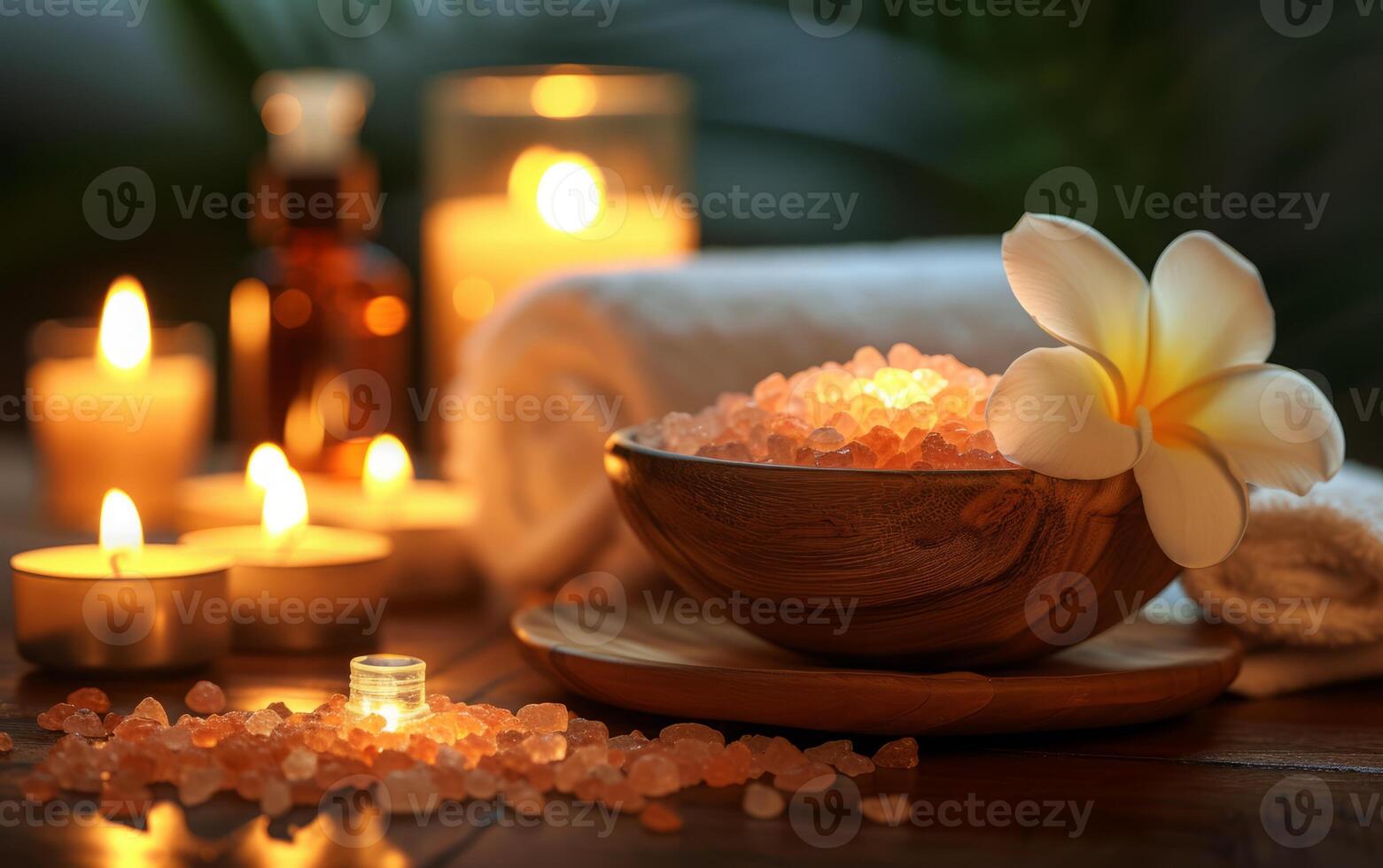 A tranquil spa arrangement featuring Himalayan salt, essential oils, frangipani blossoms, and candles photo