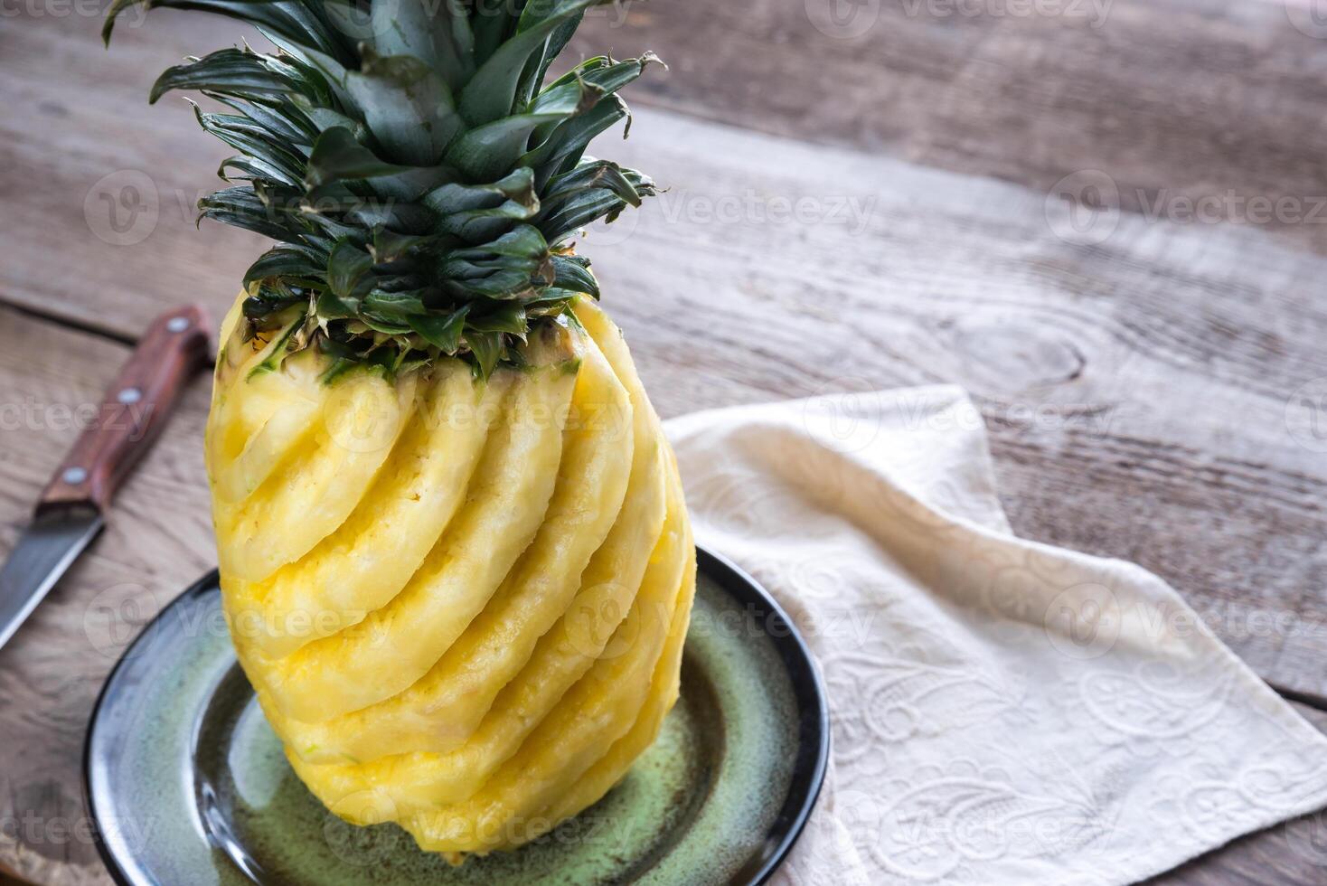 Pineapple on the plate on the wooden background photo
