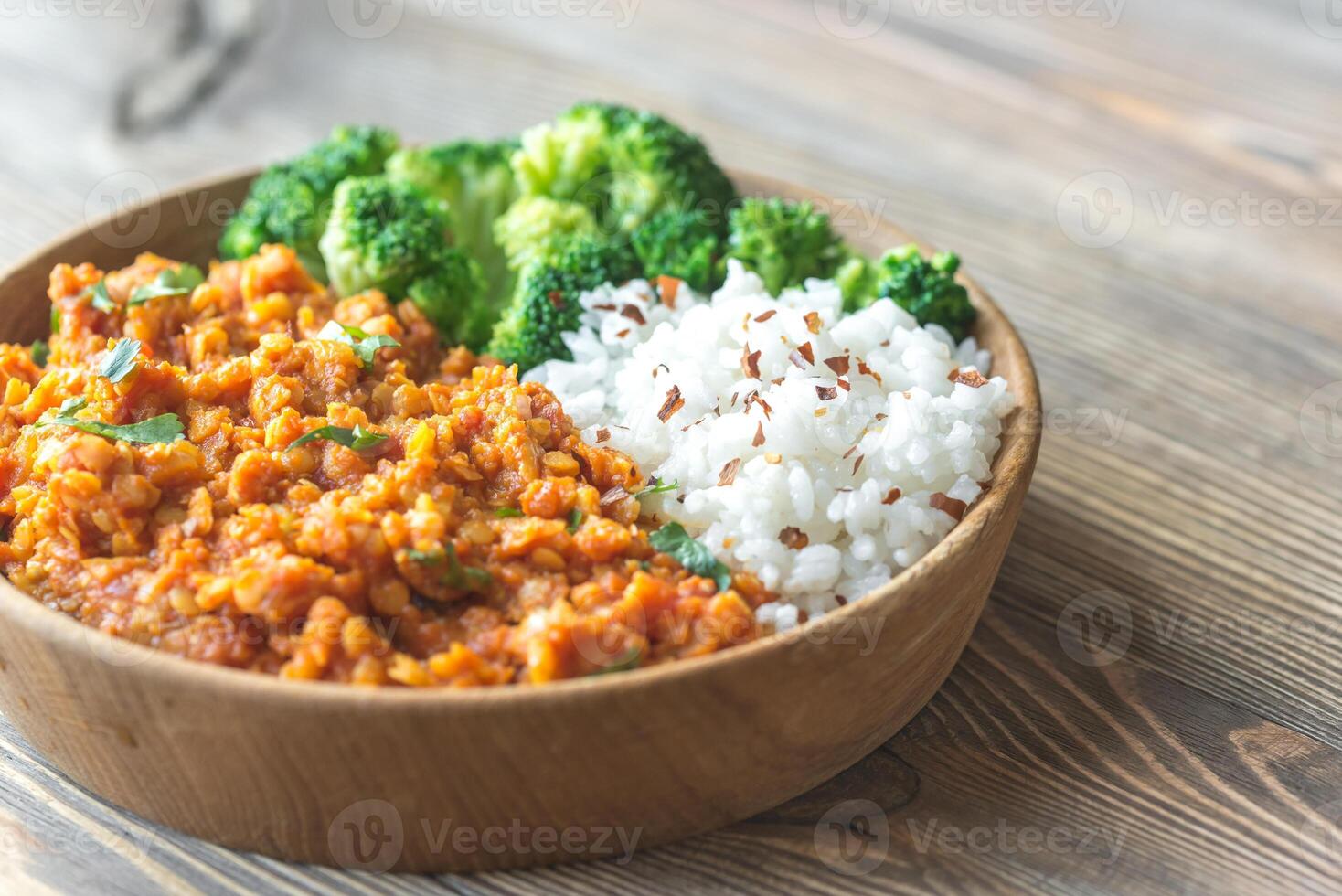 Bowl of red lentil curry with white rice and broccoli photo