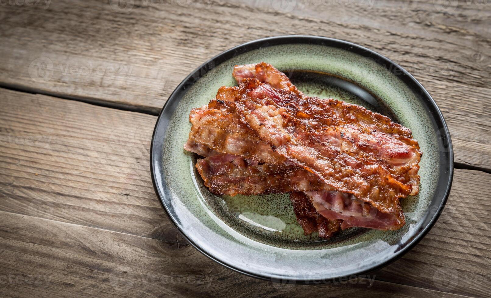 apilar de frito tocino tiras en el plato foto