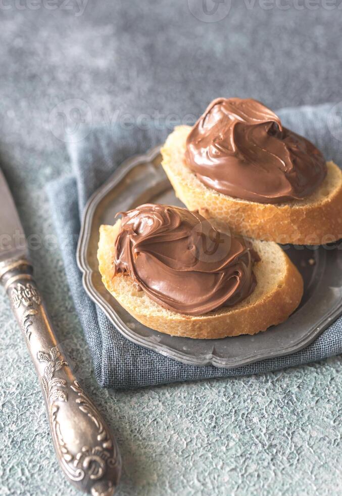 Slice of baguette with chocolate cream on the saucer photo