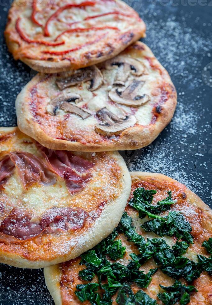 mini pizzas con varios ingredientes en la tabla de madera foto