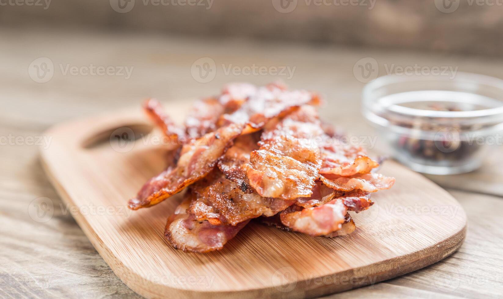 Stack of fried bacon strips on the wooden board photo