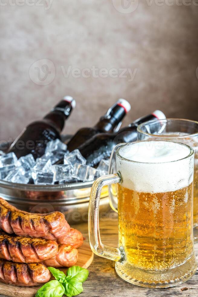 Grilled sausages and mugs of beer photo