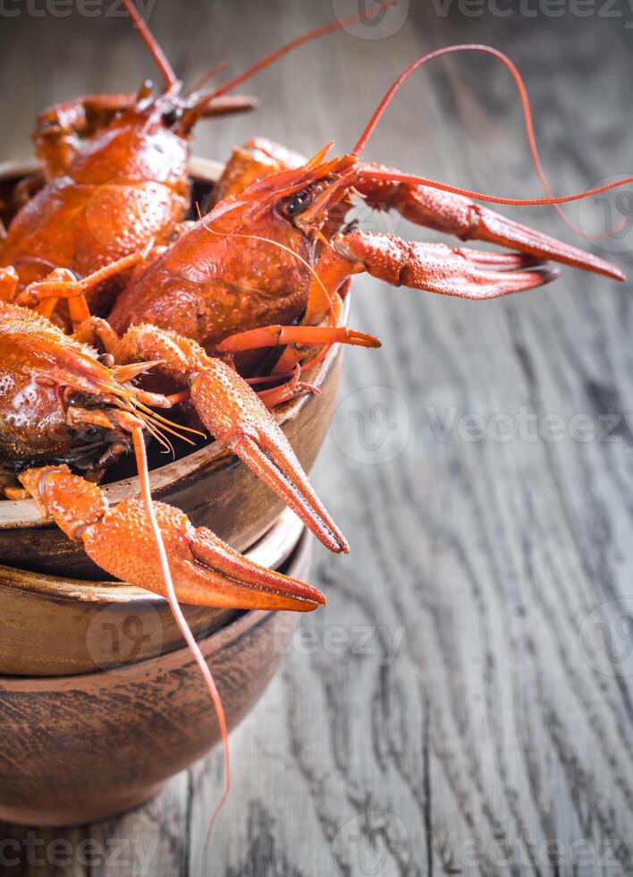 Bowl of boiled crayfish on the wooden table photo