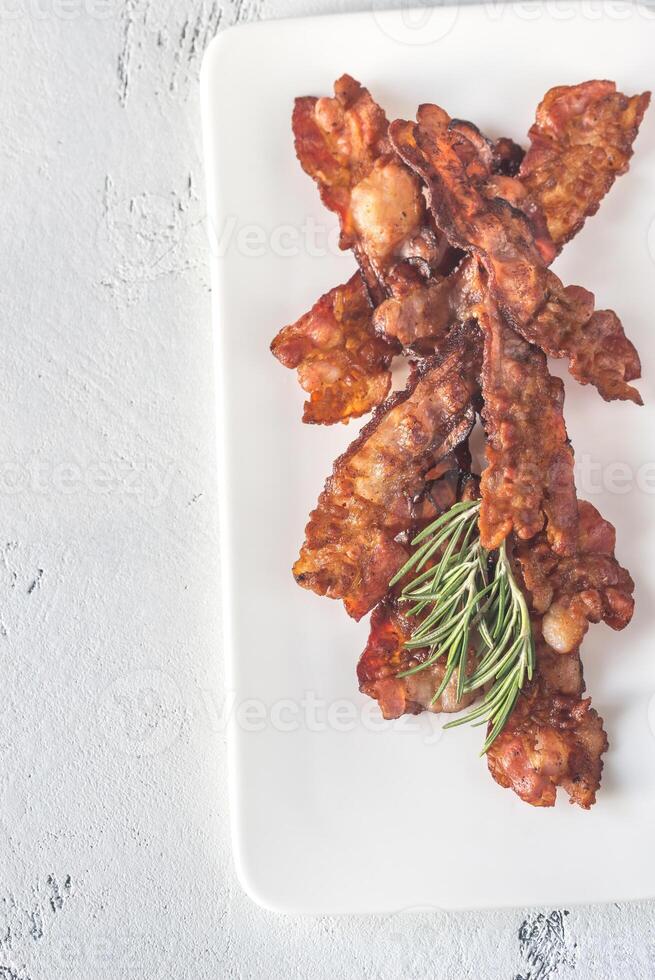 Fried bacon strips on the white plate photo