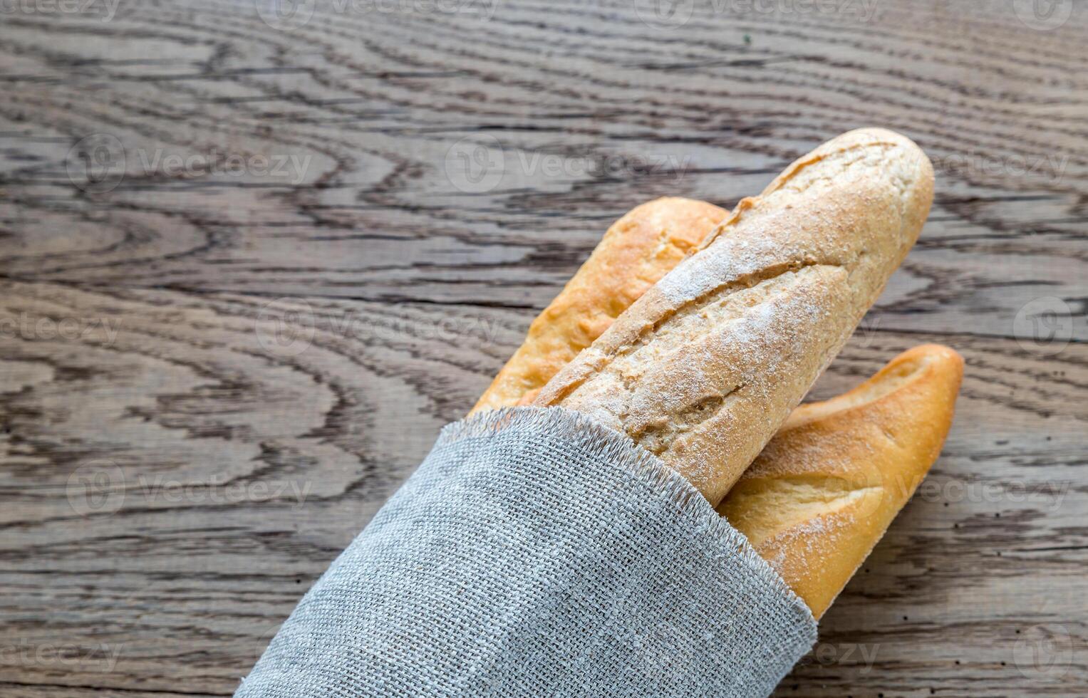 Three baguettes on the wooden background photo