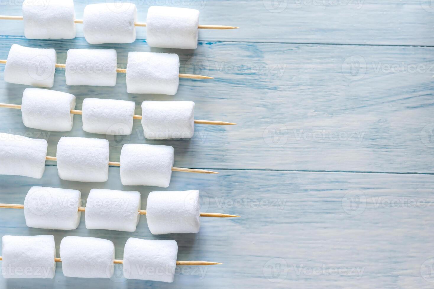 Marshmallow skewers on the wooden background photo