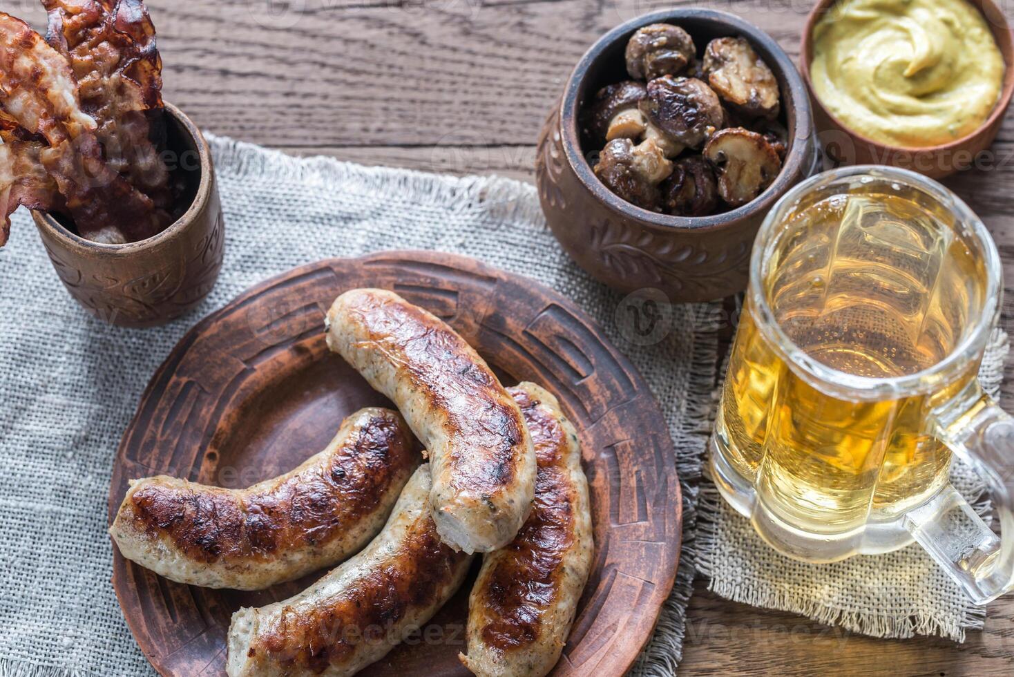 Grilled sausages with fried bacon rashers and mushrooms photo