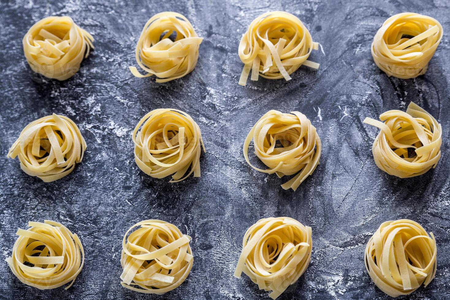 Raw tagliatelle nido on the flour-dusted black wooden background photo