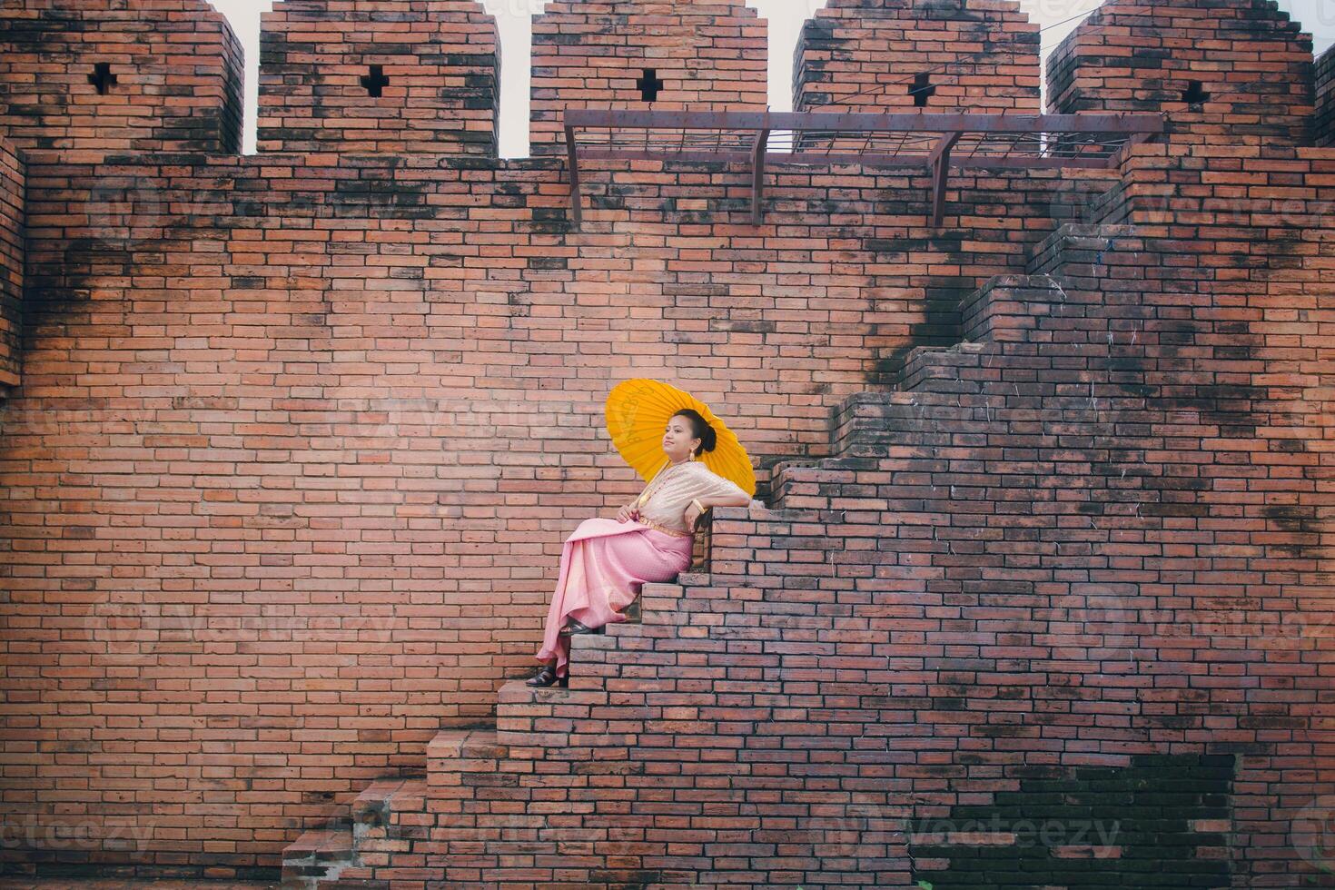 Woman sitting near a 19th century wall Tha Phae gate Old city in Chiang Mai Thailand photo