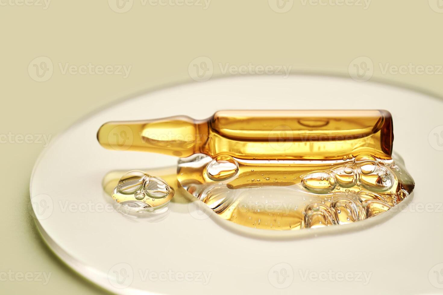 Ampoule in a drop of cosmetic gel on a green background. photo