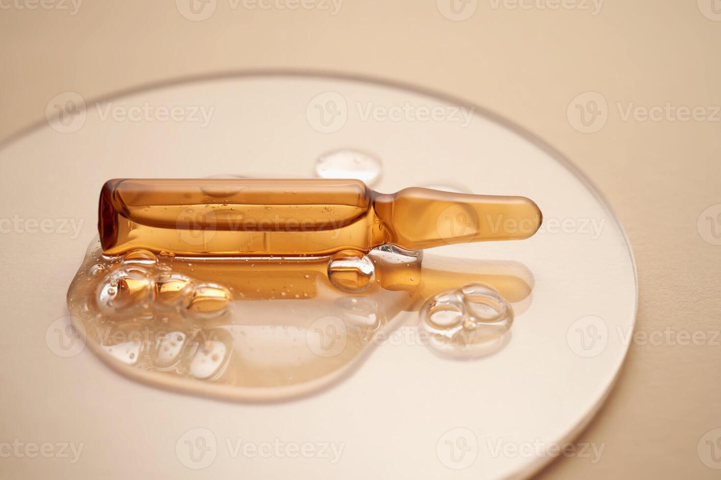 Ampoule in a drop of cosmetic gel on a beige background. photo