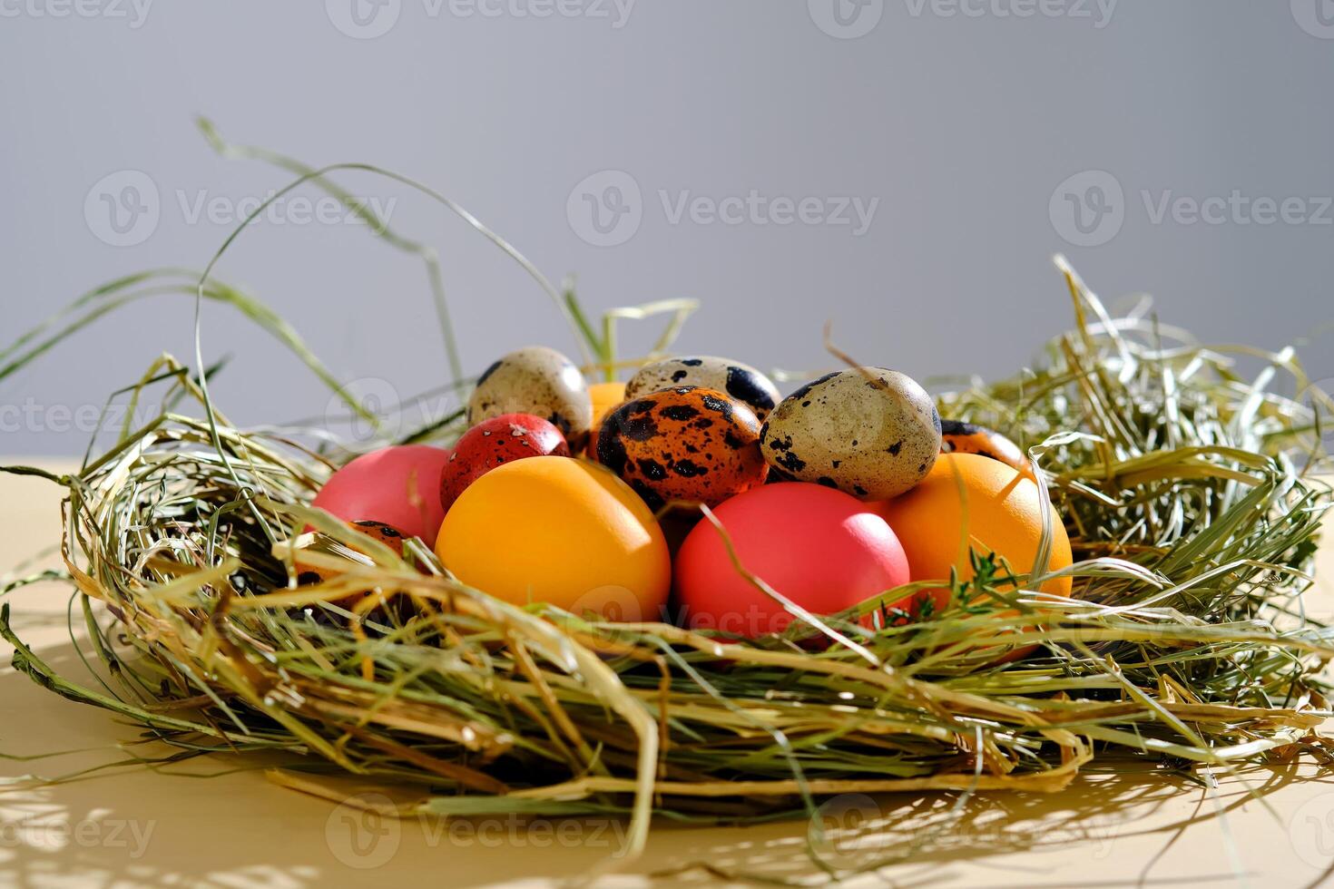 Easter eggs in pink, yellow and orange colors in a nest of grass. photo