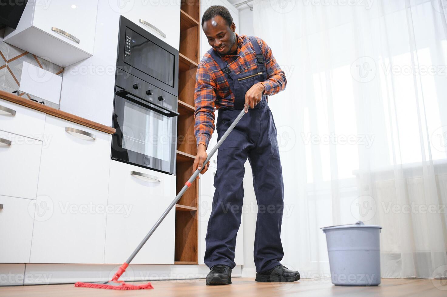 Young african man washes the floor with a mop in the room photo