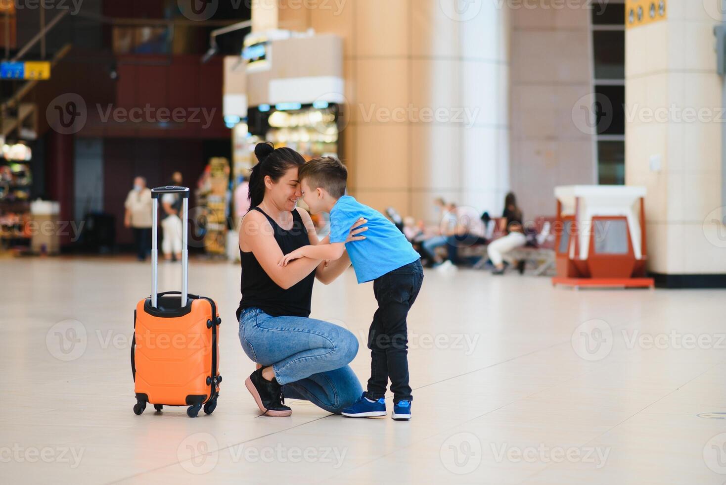 Family at airport before flight. Mother and son waiting to board at departure gate of modern international terminal. Traveling and flying with children. Mom with baby and toddler boarding airplane. photo