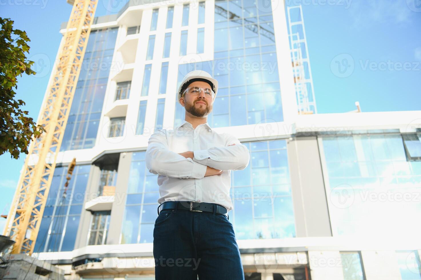 Engineer next to building cranes. Concept - large construction project. Architect directs the construction process. Drawings and tablet in the hands. photo