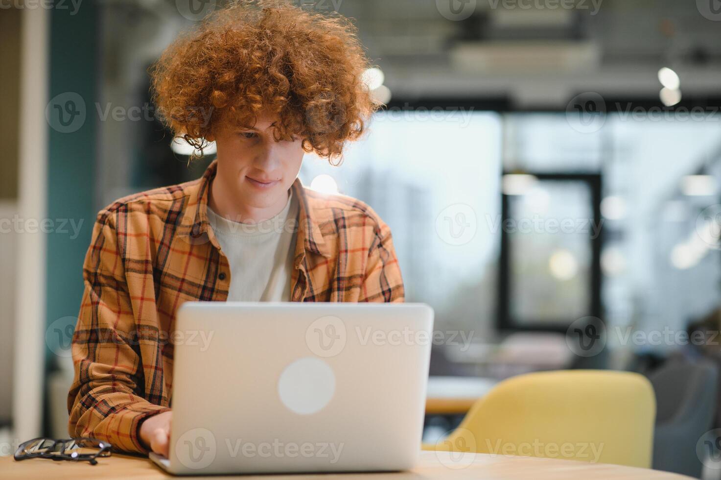 caucásico hipster chico disfrutando distancia trabajo en café comercio, masculino persona de libre dedicación en de moda lentes sentado en cafetería con moderno ordenador portátil dispositivo foto