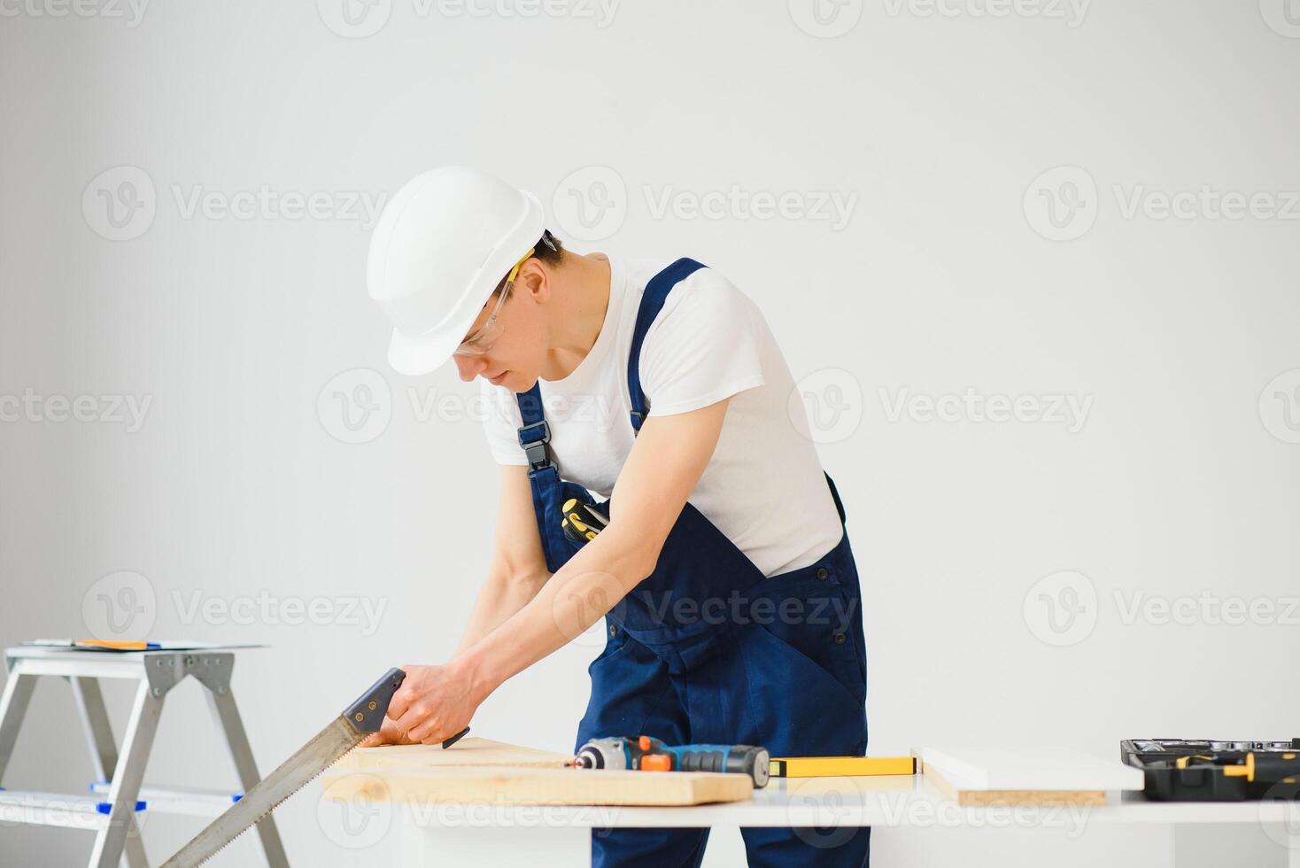 carpenter sawing white board during apartment renovating photo