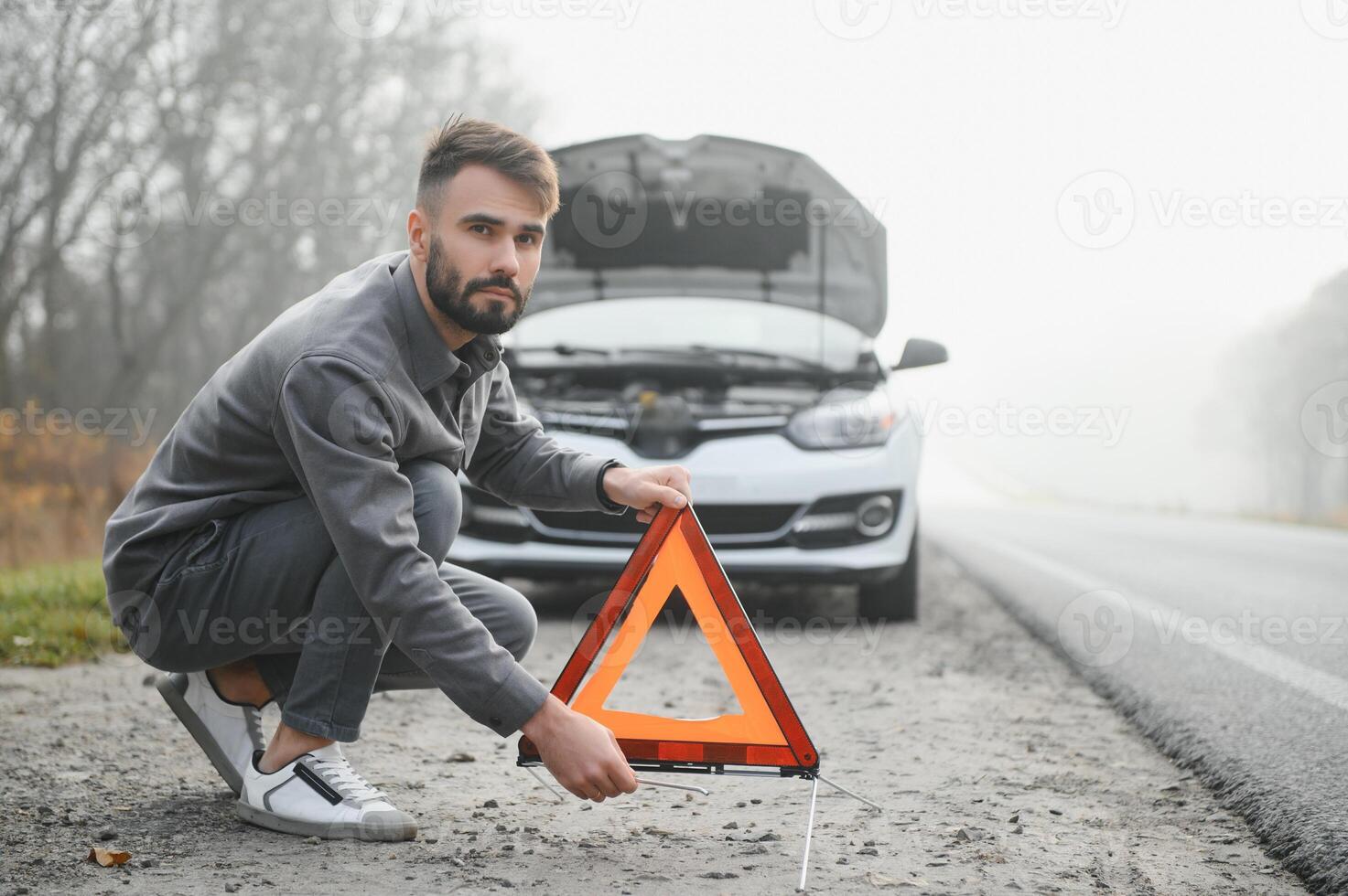 Sad man near broken car searching help in field photo