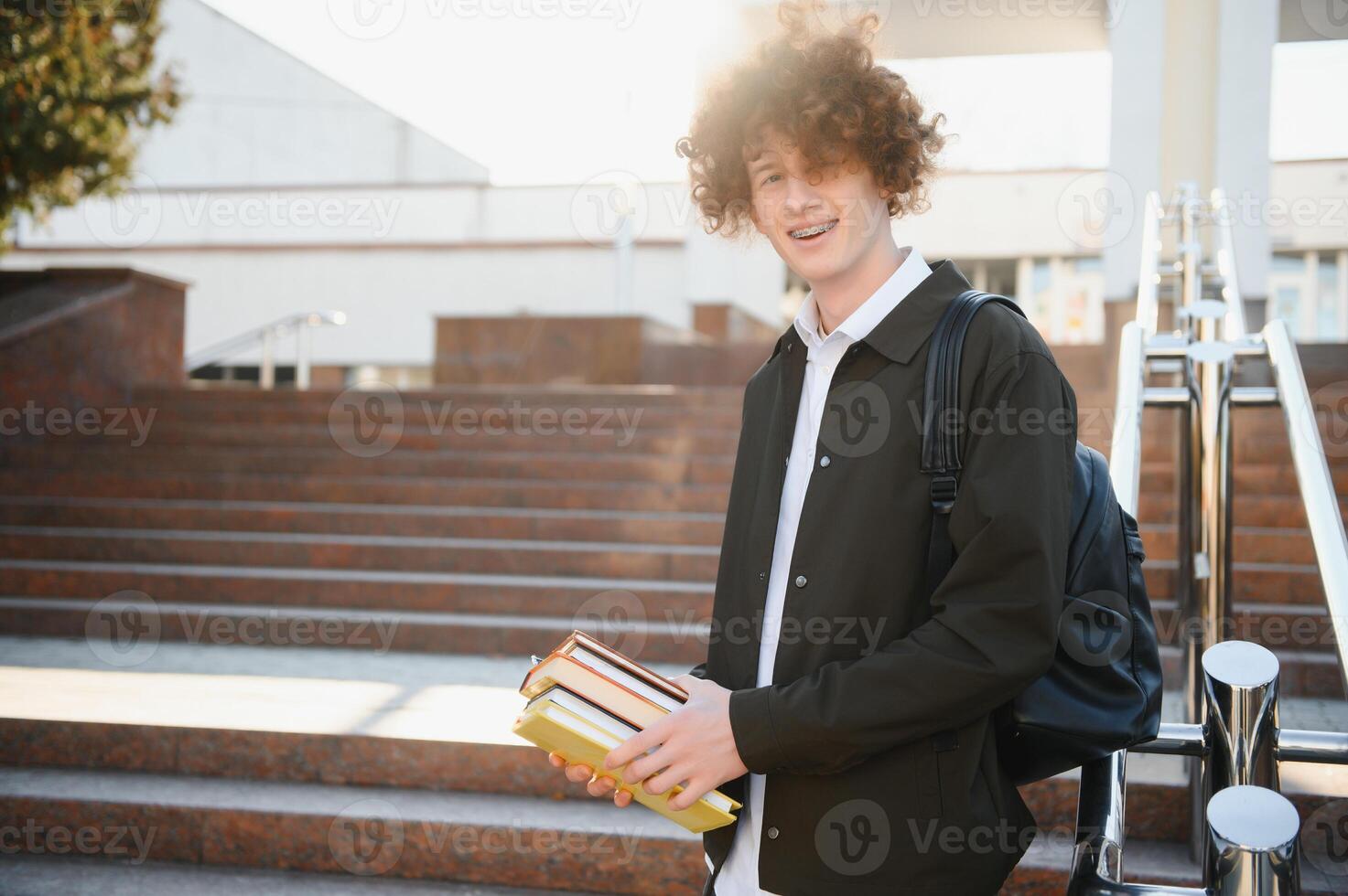 University.Smiling young student man holding a book and a bag on a university background .Young smiling student outdoors Life style.City.Student. photo