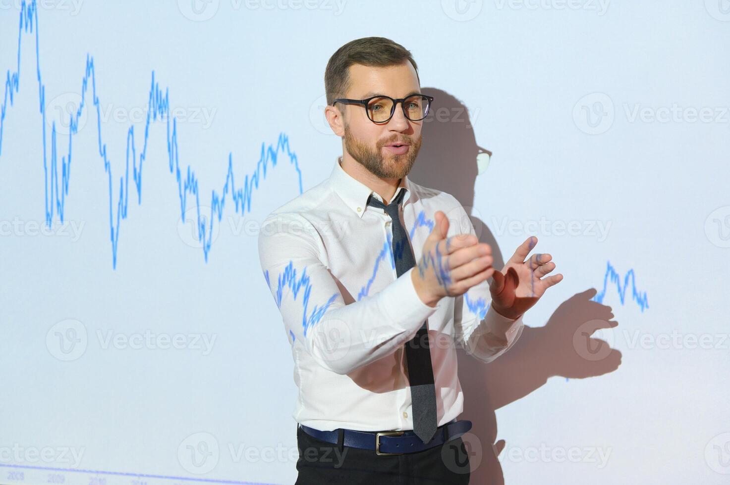Man is standing near projector and showing graphs and business graphs. photo