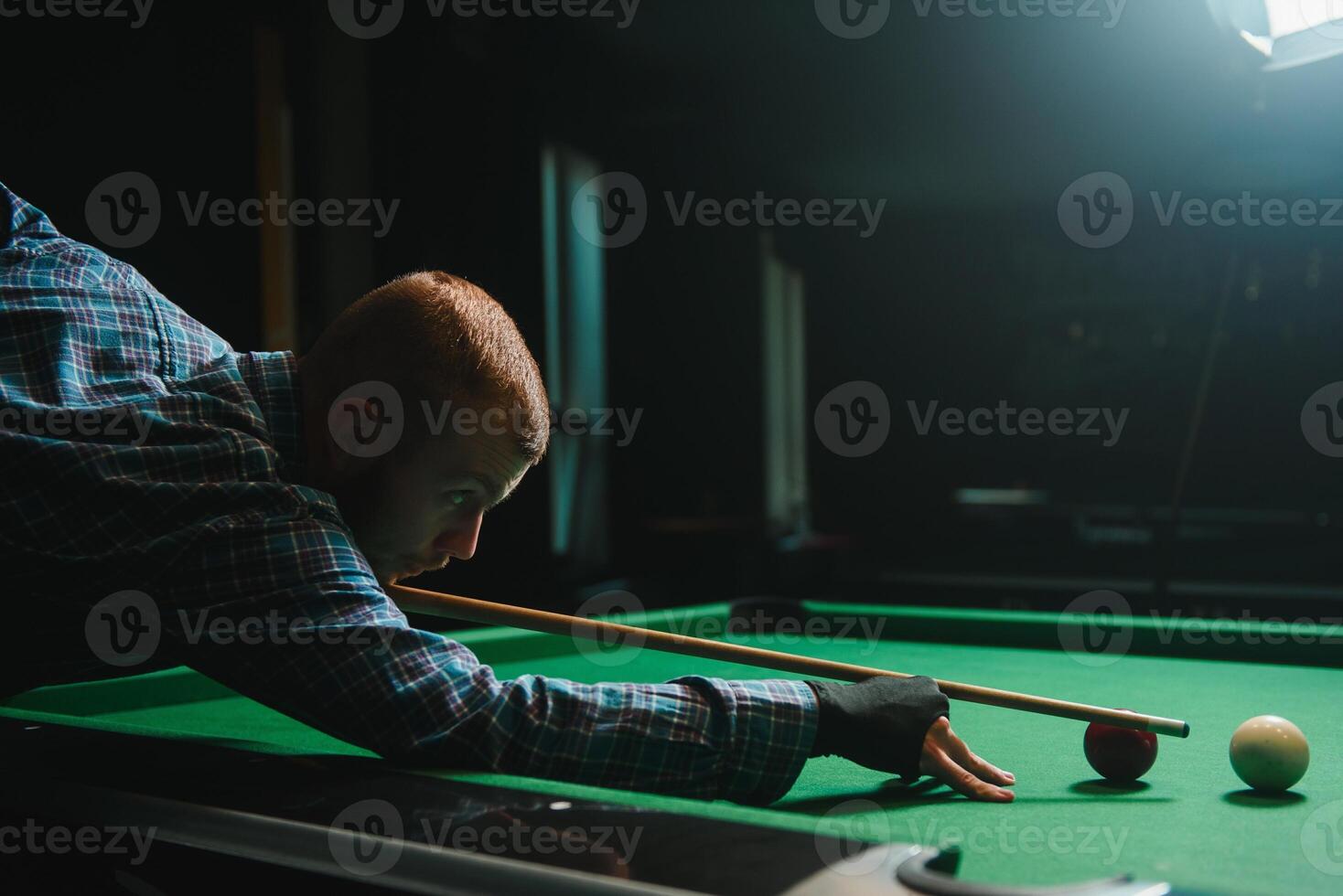 Young man playing billiards in the dark billiard club photo