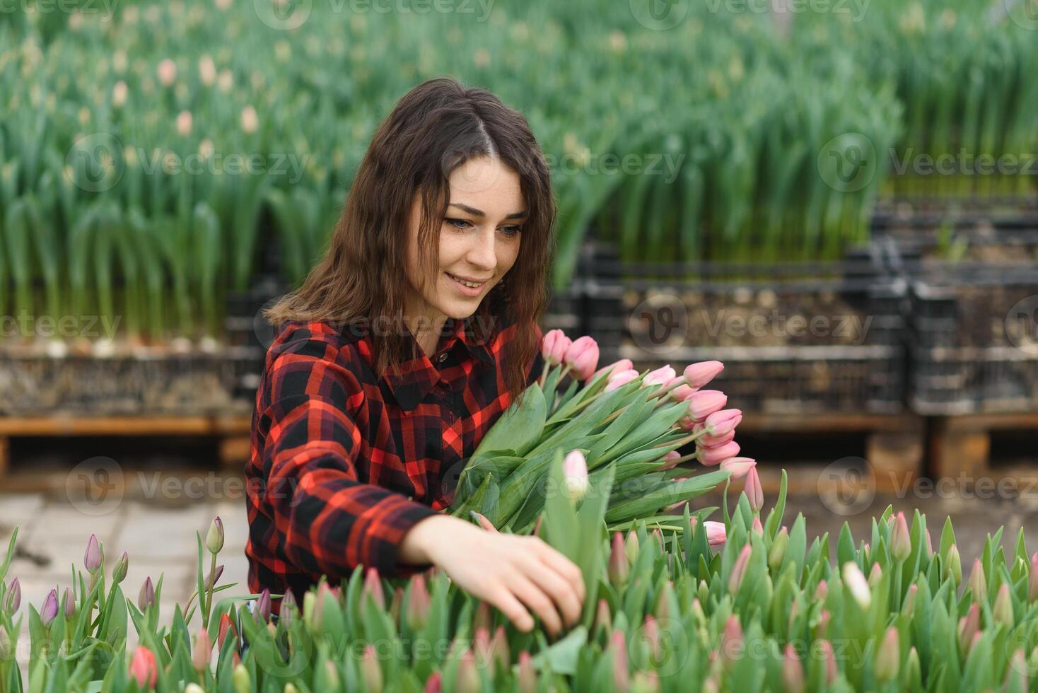 Beautiful young smiling girl, worker with flowers in greenhouse. Concept work in the greenhouse, flowers. photo