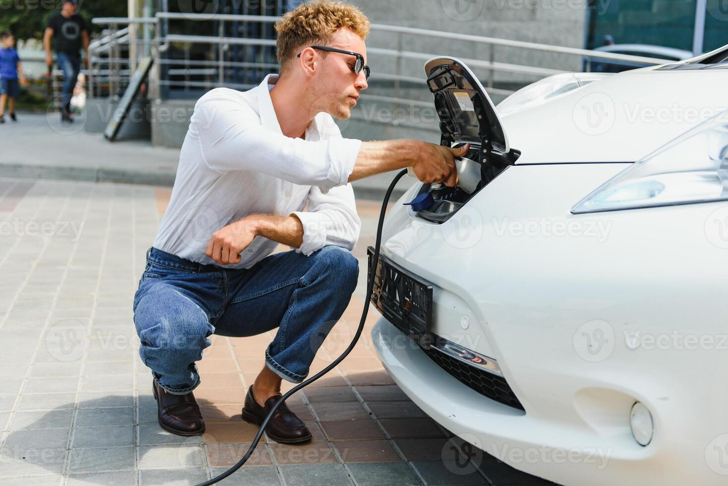 Smiling man unplugging the charger from the car photo