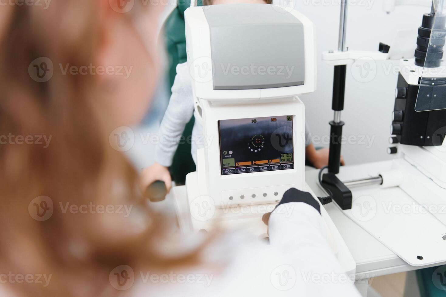 Modern medical equipment. Close up of ophthalmologist using auto refractometer while examining child eyes. photo