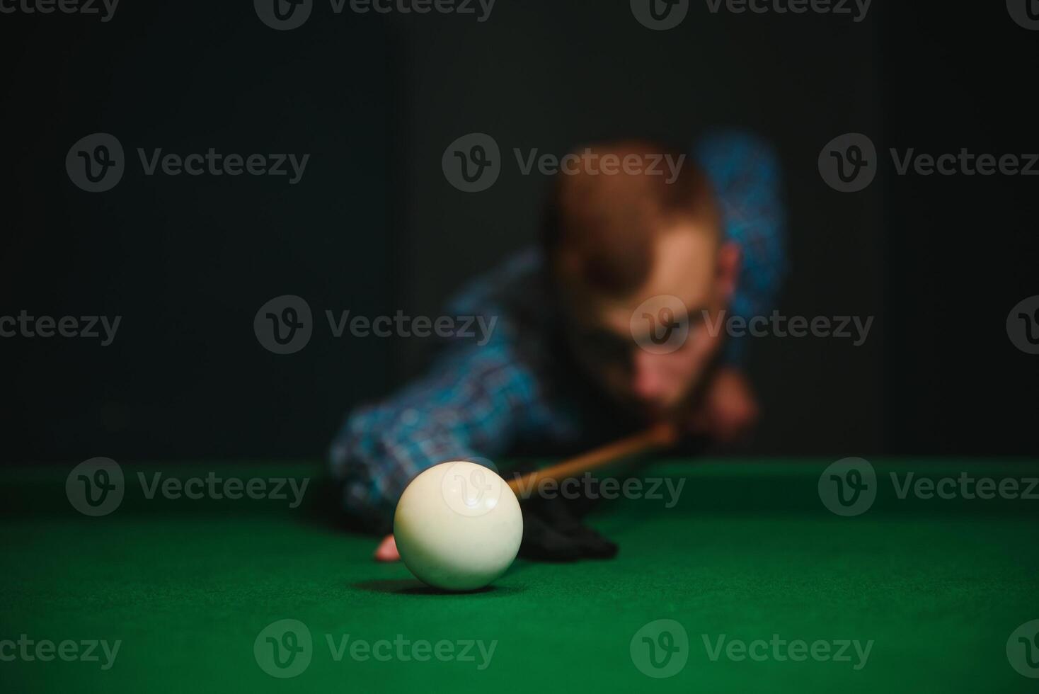 Young handsome man leaning over the table while playing snooker photo