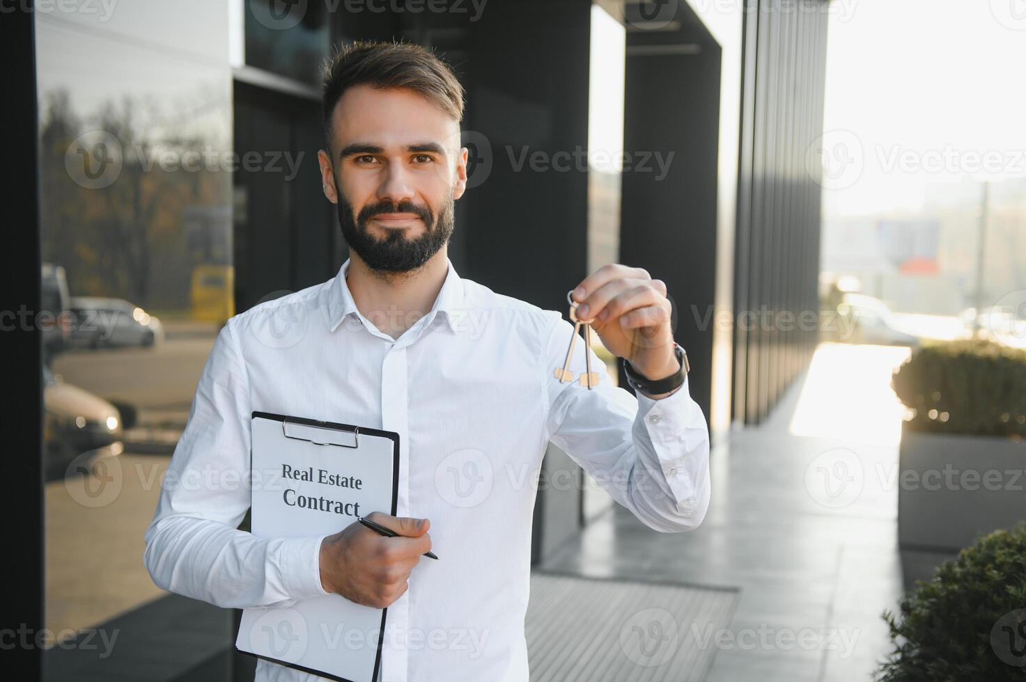 Real estate agent holding key on blurred background, closeup photo