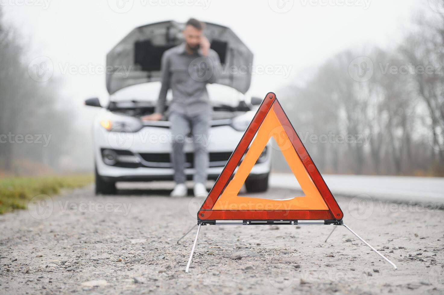 Man use a cellphone call garage in front of the open hood of a broken car on the road in the forest. Car breakdown concept. photo